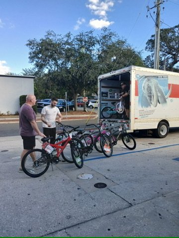 Volunteers staging newly donated bicycles in a line next to an open U-Haul truck.