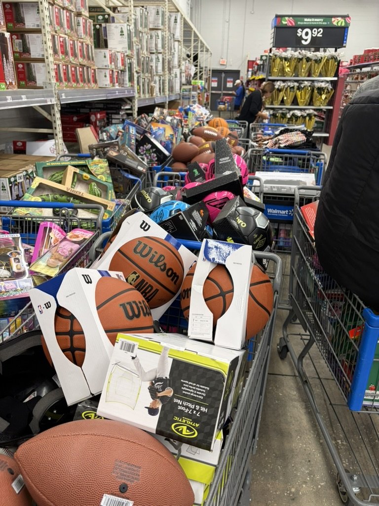 Shopping carts packed with Wilson basketballs, footballs, soccer balls and sports gear during the drive's Walmart shopping trip.